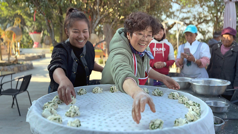 【2】旅居者趙發(fā)英（圖左二）教曼海村村民做花卷。陶思源-攝